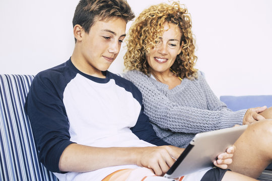 cheerful and happy family at home studying on a tablet internet connected. bright image of caucasian people mother and son together looking a technology device for study or pleasure