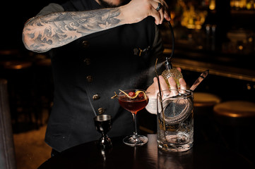 Bartender with tattoo making a fresh and sweet summer cocktail with cherries