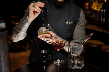 Barman with tattoo making a fresh and sweet summer cocktail with cherries