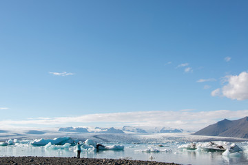 Island , Frau steht mit Blick auf den Gletscher und erhobenen Armen am Gletschersee