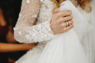 Bride holds a veil in the arm with wedding rings