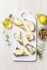 Pear and brie, honey crostini toasts on marble background. Top view, space for text.