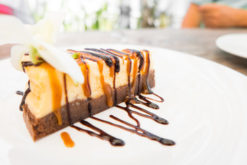 Cheesecake slice with melted and crushed chocolate in white dish,sweet dessert.