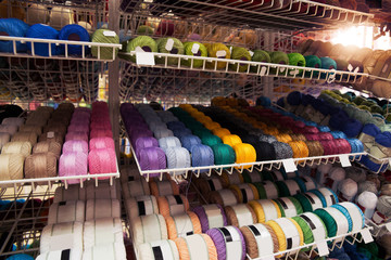 Many multi-colored threads on the shelf of the store.