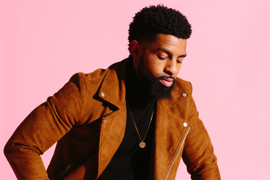 Stylish, handsome and cool African American man with beard, isolated on pink studio background