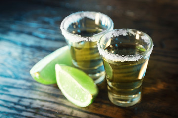 Tequila and lime in the defocus in a bar on a wooden background