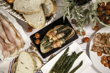 bodegón esparragos y bacon sobre fondo de madera blanco