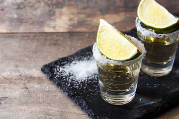 Mexican Gold tequila with lime and salt on wooden table. Copyspace
