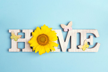 Decorative word Home with butterflies and sunflower on blue background.
