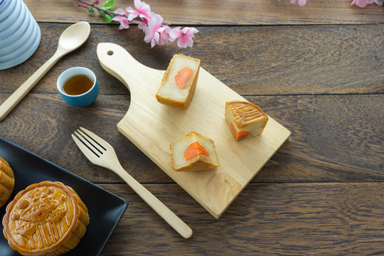 Close up image of food dessert decorations Chinese Moon Festival background concept.Food & drink of meal set cake & cup tep and pink blossom on modern rustic wooden plank.Free space for design  text.