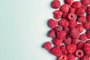 Fresh raspberries on blue background with copy space.