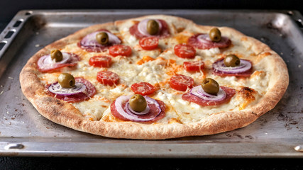 Italian pizza with cheese and olives on a baking sheet. Close-Up