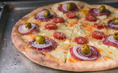 Italian pizza with cheese and olives on a baking sheet. Close-Up