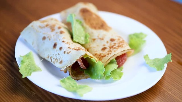 thin pancakes with salad leaves and bacon in a plate