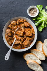 Delicious beef stew. Healthy seasonal comfort food on a dark background, top view. Flat lay, copy space