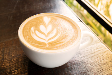 Cup of latte art coffee on wooden table in the coffee shop