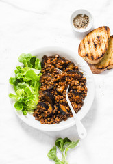 Lentils eggplant stewed in tomato sauce on light background, top view. Healthy seasonal vegetarian lunch