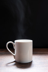 White coffee cup on wooden table with dark background