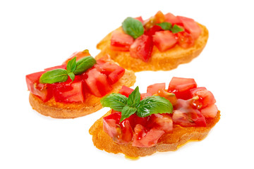 savory bruschetta with chopped tomato, green leaf of basil and olive oil isolated on white...