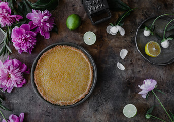 top view of tasty lemon pie and violet peonies on wooden table