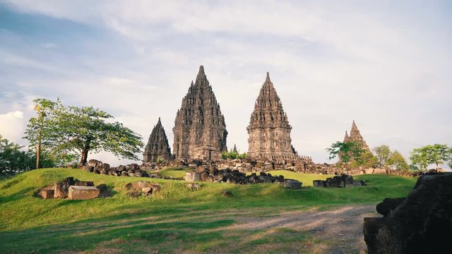 Prambanan temple, green tree and lawn in Jogjakarta, Indonesia on sunny evening, slide left