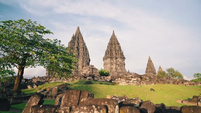 Prambanan temple and green tree and lawn in Jogjakarta, Indonesia on sunny evening, slide right
