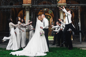 Friends have fun on the background while newlyweds kiss before them