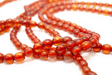 Amber. Beautiful bright beads of petrified resin on a white background. Amber texture and background. Jewelry product of natural and fashionable amber mineral.  Sun stone. Crystal. Bokeh effect