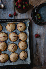 elevated view of cooked yummy cookies with strawberries on tray
