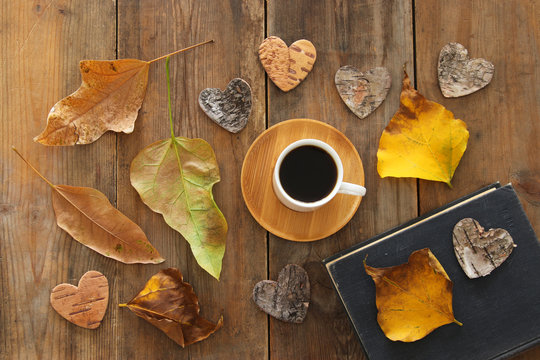 top view image of coffee cup over wooden , dry autumn leaves and stack of book.