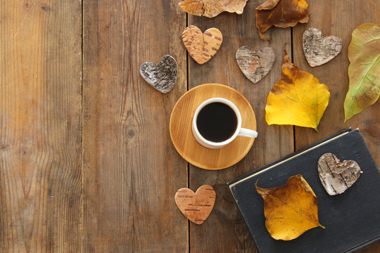top view image of coffee cup over wooden , dry autumn leaves and stack of book.