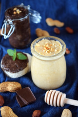 White and chocolate peanut urbech in glass jars surrounded by the ingredients. Top view