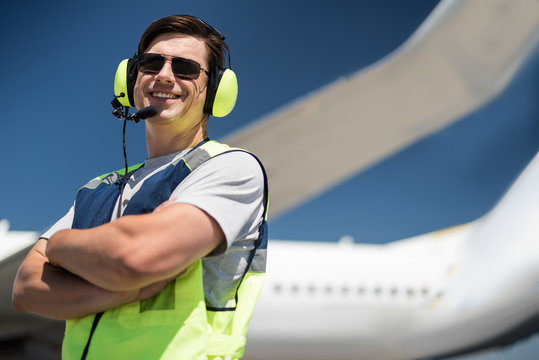 Nice shot. Low angle portrait of ground crew member smiling and posing near passenger plane. Copy space in right side