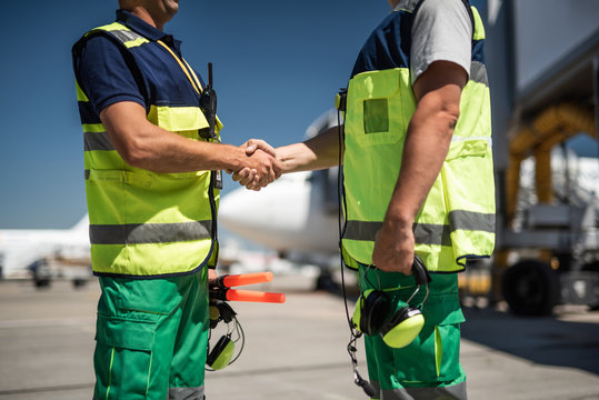 Good to see you. Aviation marshaller greeting colleague. Focus on handshake