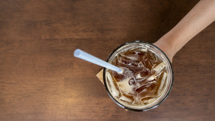 Close up woman hand holding ice black coffee in coffee shop