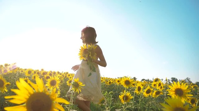 Happy little girl running happy free across the field with sunflowers. slow motion video. smelling big sunflower on summer field. lifestyle Delight of a pleasant smell. Summer holiday. concept