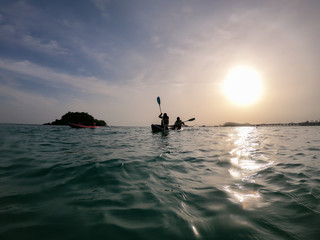 Fototapeta premium Seascape with kayakers at sunset. silhouette man in the kayak on the ocean in front of dramatic sundown
