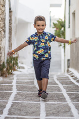 Little cute child doing balance on the street of a Greek village