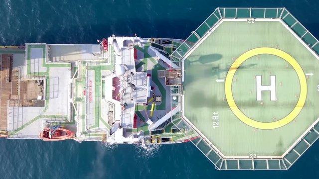 Aerial footage of a Medium size red Offshore supply ship with a Helipad and a large crane