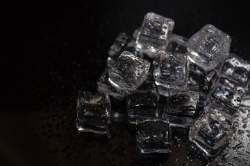 Top view of ice cubes reflection on black table background. Pile of different ice cubes on...