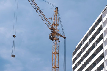 Construction of a multi-storey building. House and construction crane on sky background.