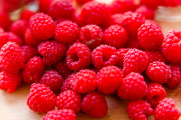 Juicy raspberries lying on wooden cutting board macro