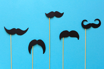 Paper mustache on booth props on blue paper background. Cut out style. Movember concept. Top view....