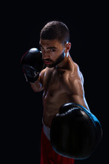 Man is hitting an opponent. Focused fighter with naked torso and boxing gloves looking at the...
