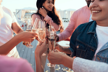 Outgoing women and cheerful males tasting delicious champagne while speaking together during party
