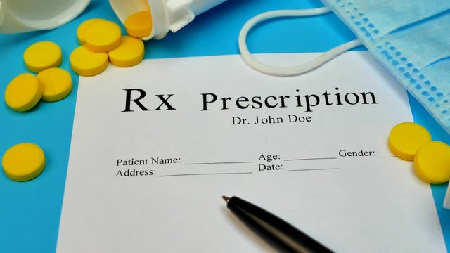 Prescription for tablet pills or drugs on blue background with bottle and yellow tablets or pills and medical mask