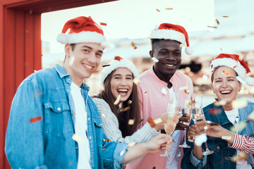 Portrait of beaming young men and satisfied girls telling while clanging glasses of champagne. They looking at camera. Glad comrades during party concept