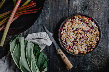 elevated view of yummy pie with berries and rhubarb on wooden table