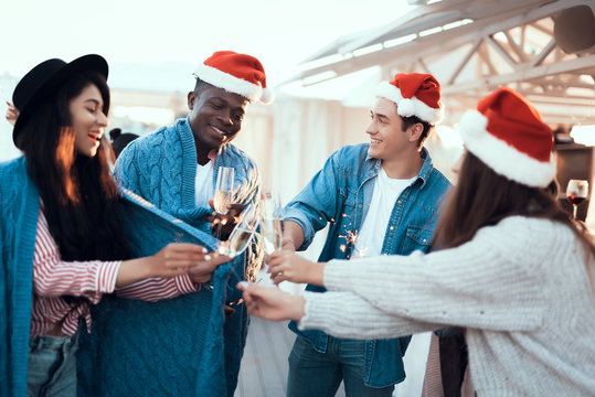Positive women and smiling men clanging glasses of champagne while communicating during party. Glad comrades having fun during christmas concept