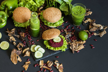 Vegan burgers with beet cutlet and green smoothies on black background. Healthy vegan food. Detox diet.